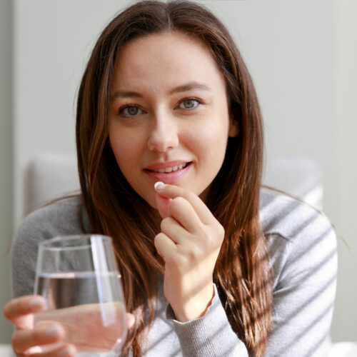 Smiling young woman taking medication at home